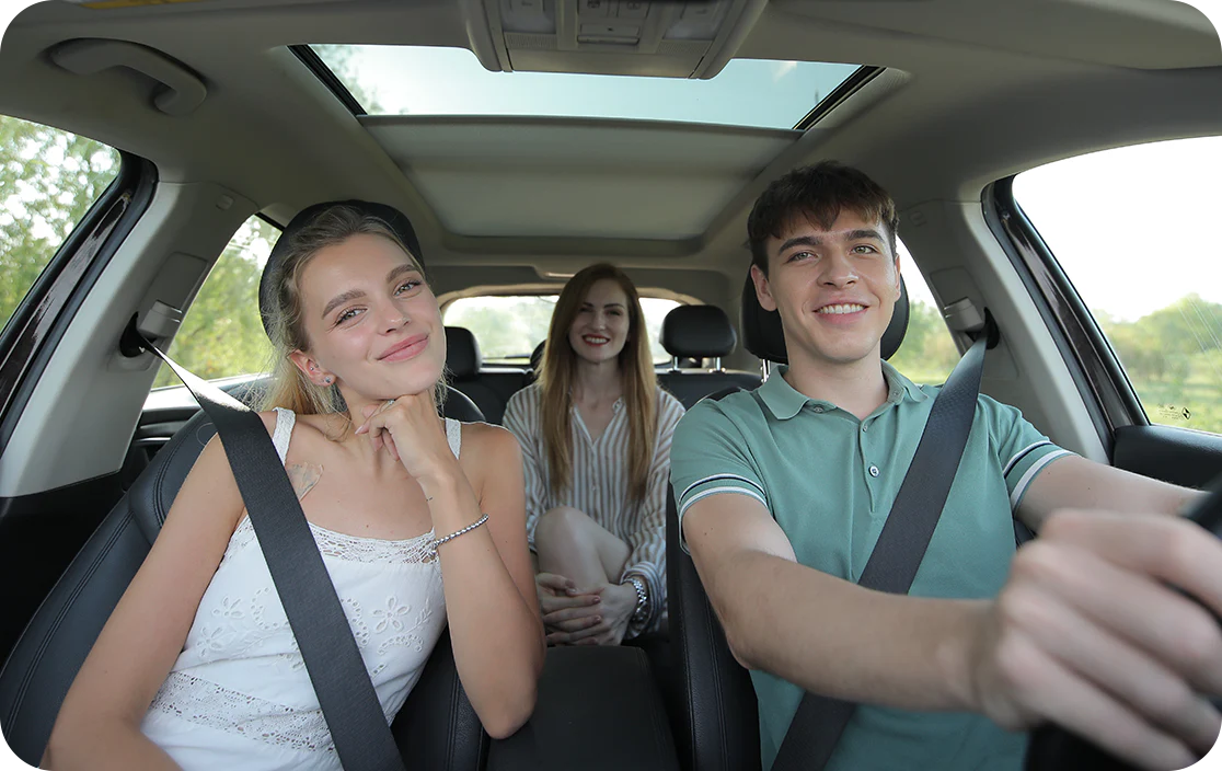 Three friends in a car, smiling and enjoying a ride.