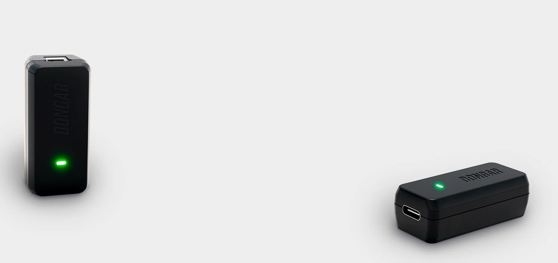 Two black electronic devices with green lights on a light gray background