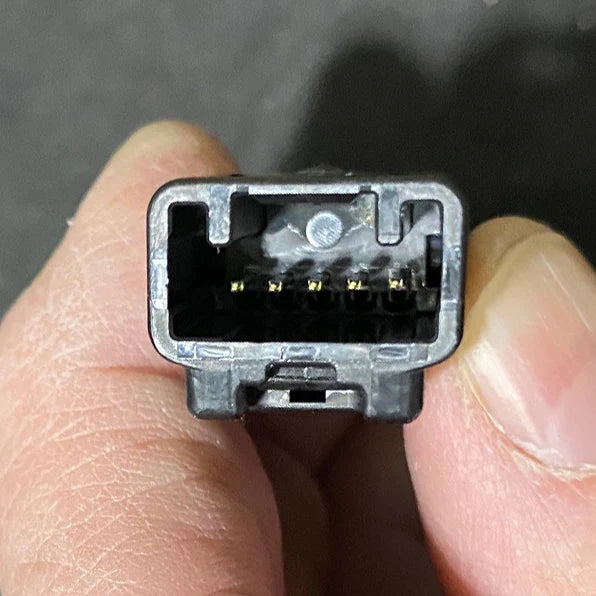 Close-up of a small electronic connector held between fingers against a dark background