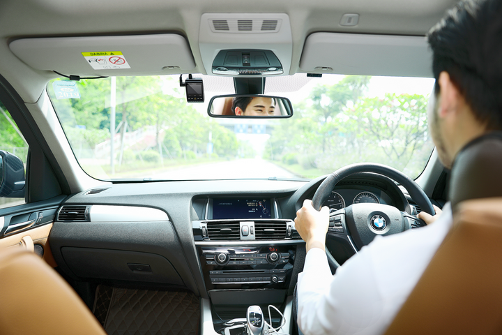 Person driving a car with a focus on the interior dashboard and steering wheel.