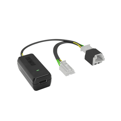 Dongar hardwire module with glowing green light and off-white connectors revealing copper terminals, wired with yellow and green conductors for clear visibility