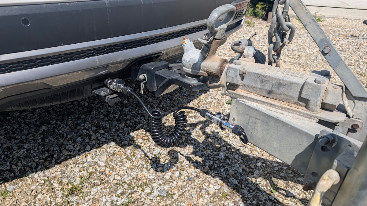Coiled extension cable connecting vehicle bumper to trailer hitch