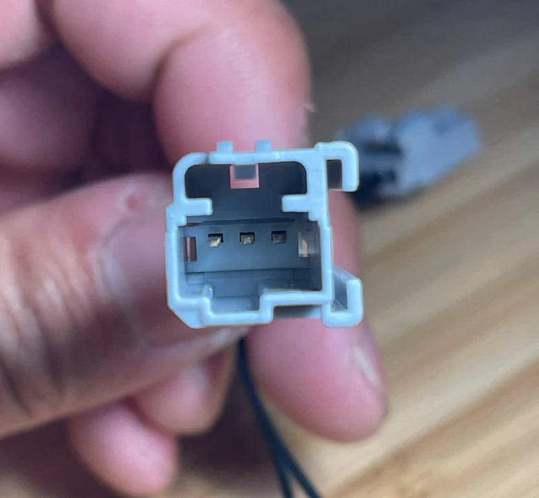Close-up of a small electronic component held between fingers on a wooden surface