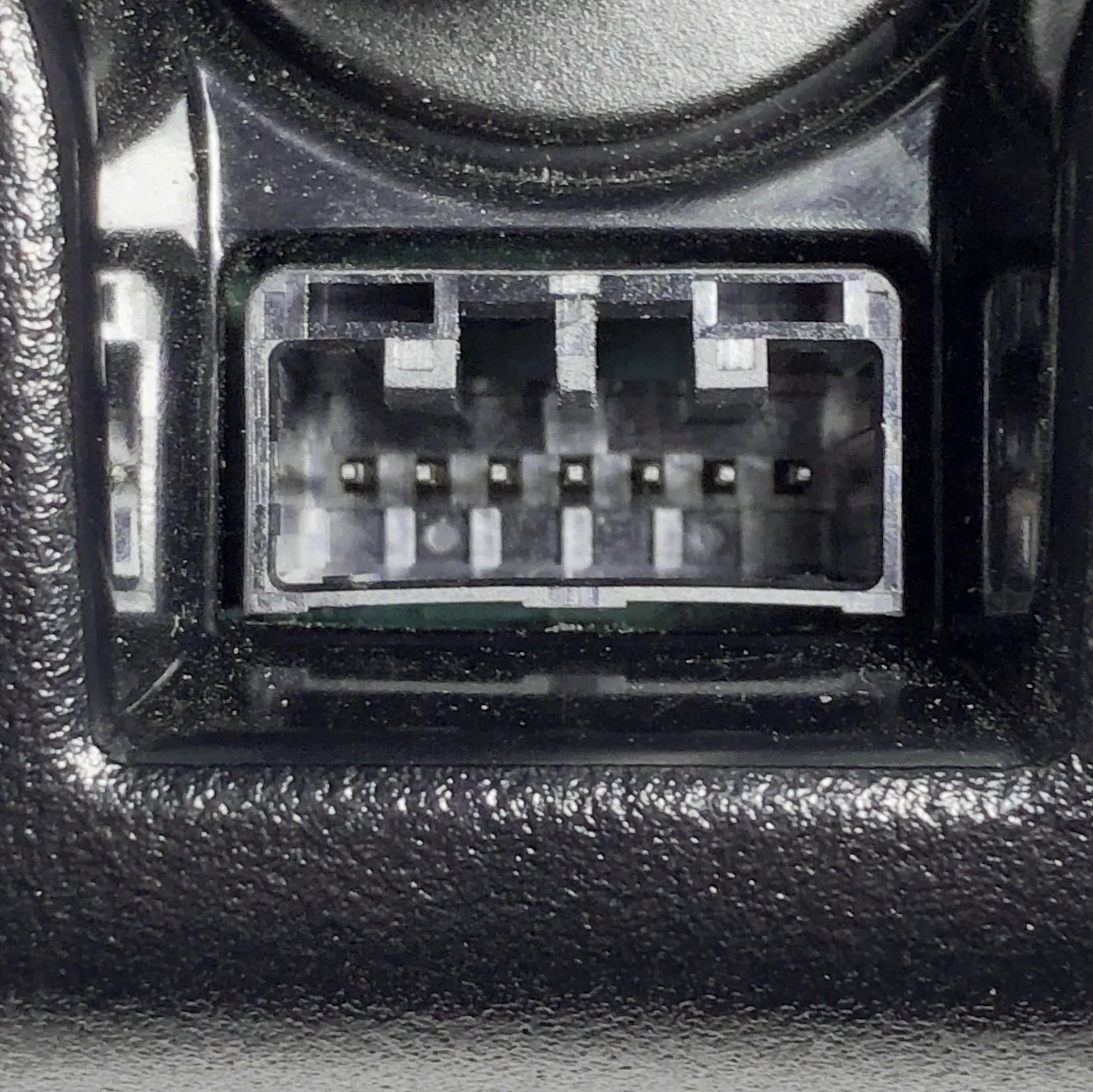 Close-up of a car audio connector socket with visible pins on a textured black background.