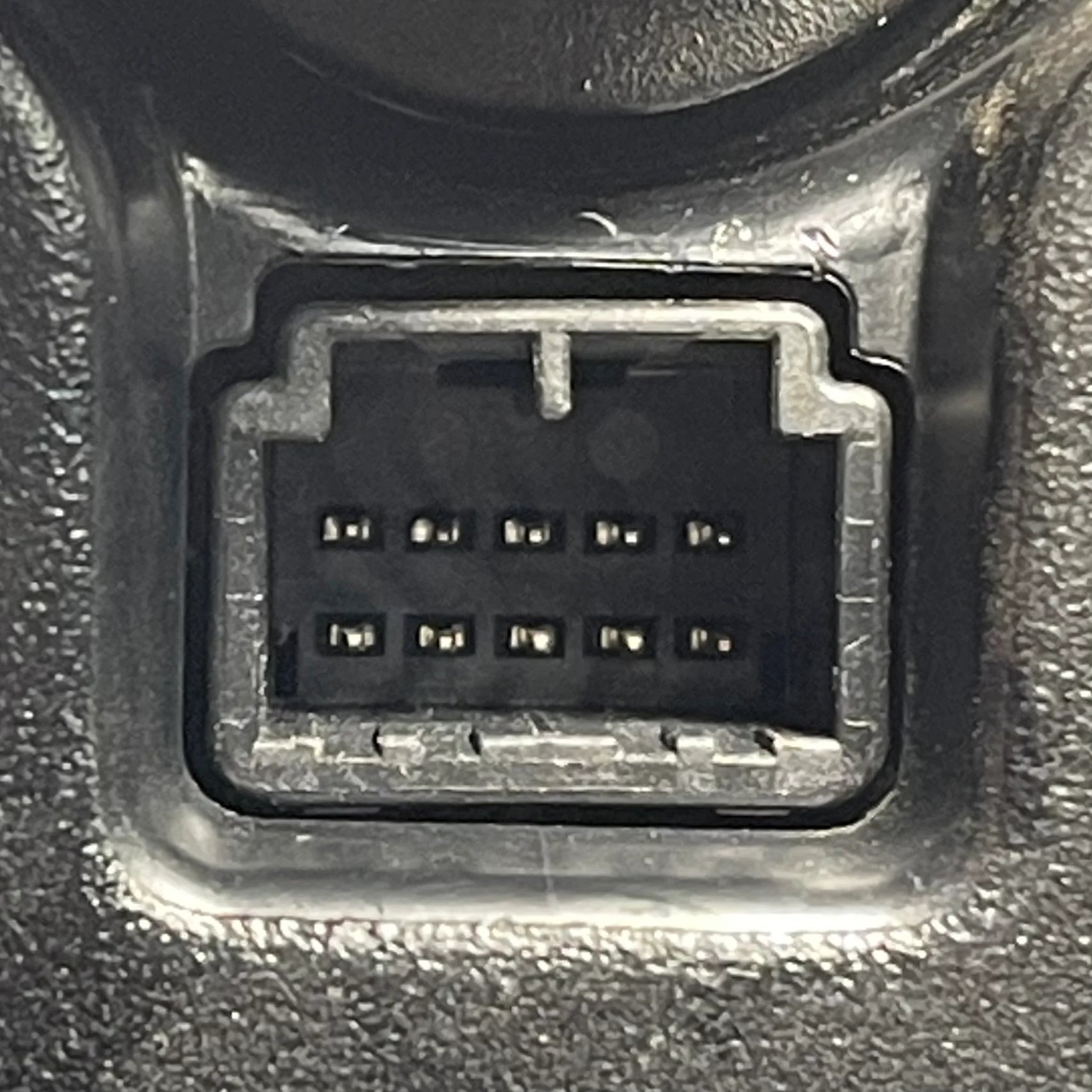 Close-up of a car diagnostic connector socket on a metallic surface.