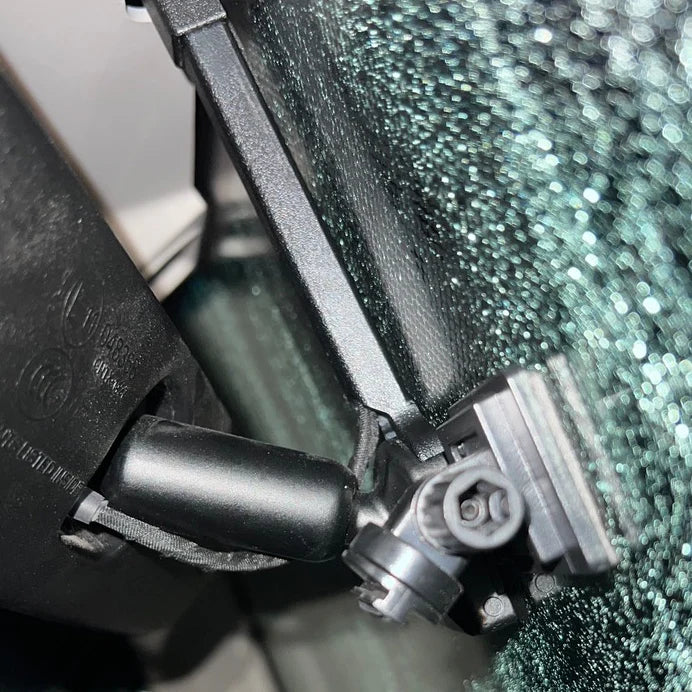 Close-up of a car's windshield wiper mechanism with a blurred background